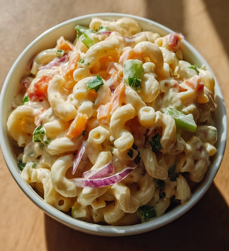 A bowl of macaroni salad with onions and peppers.