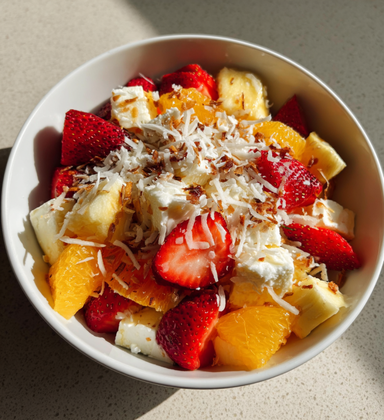 A bowl of fruit salad with strawberries, bananas, and oranges.