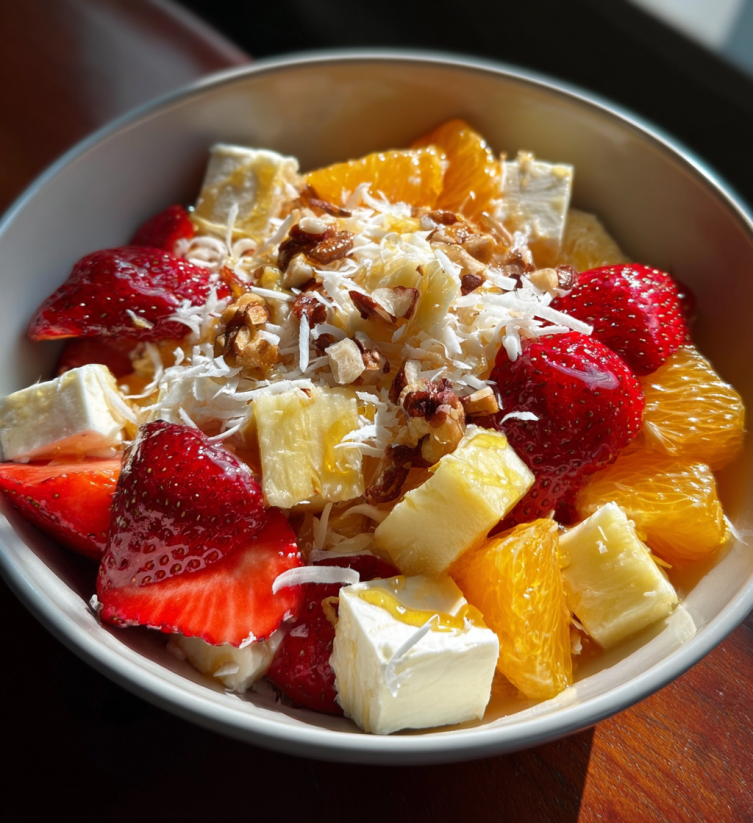 A bowl of fruit salad with strawberries, oranges, and bananas.