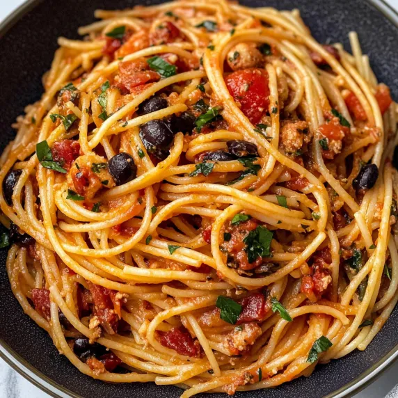 A bowl of spaghetti with meatballs and tomatoes.