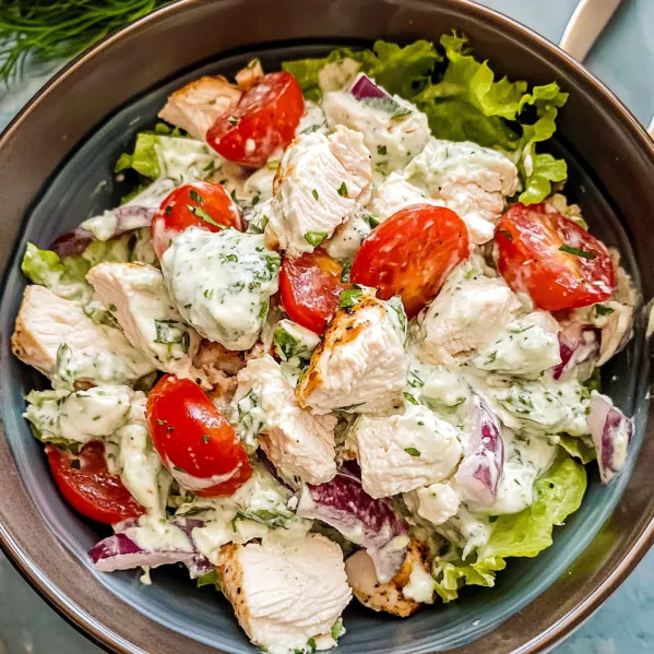 A bowl of chicken salad with tomatoes.