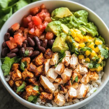 A bowl of food with rice, chicken, beans, tomatoes, avocado, and corn.