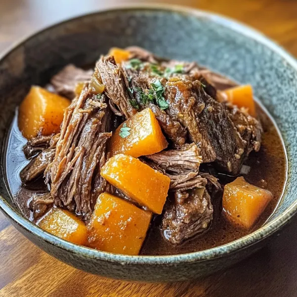 A bowl of beef stew with carrots and onions.