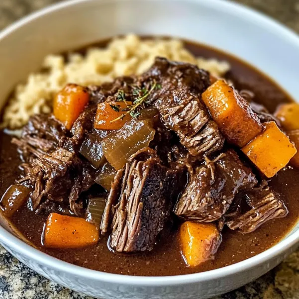A bowl of beef stew with carrots and onions.
