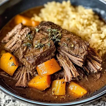 A bowl of beef stew with carrots and rice.