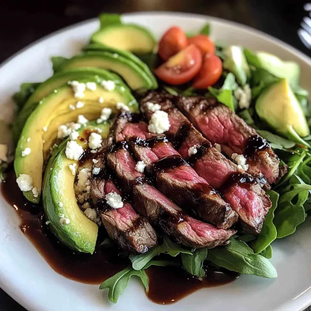 A plate of food with meat, avocado, tomato, and lettuce.