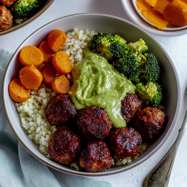 A bowl of food with meatballs, broccoli, carrots, and rice.