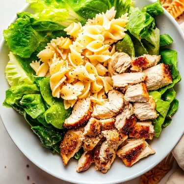 A bowl of pasta salad with chicken and lettuce.