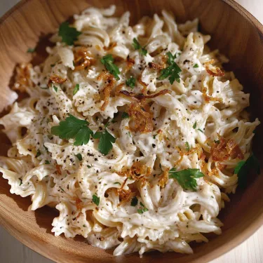A bowl of pasta with cheese and herbs.