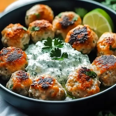 A bowl of meatballs with a dollop of sour cream on top.