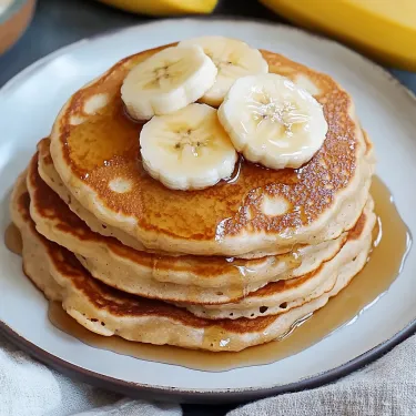 A stack of pancakes with bananas on top.