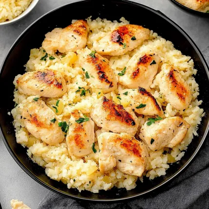A bowl of rice with chicken and vegetables.