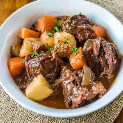 A bowl of beef stew with carrots and potatoes.