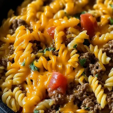 A bowl of pasta with meat and tomatoes.