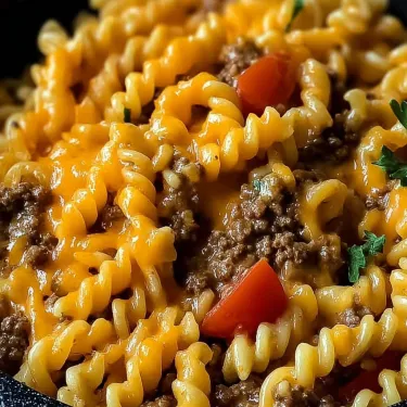 A bowl of pasta with meat and tomatoes.