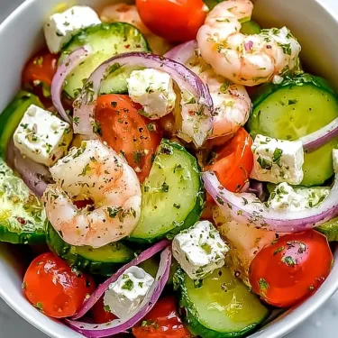 A bowl of shrimp, tomatoes, cucumbers, and feta cheese.
