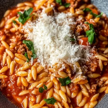 A bowl of pasta with cheese and meat.