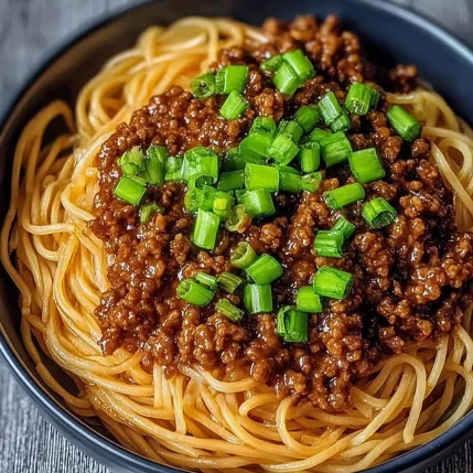 A bowl of spaghetti with meat sauce and green onions.
