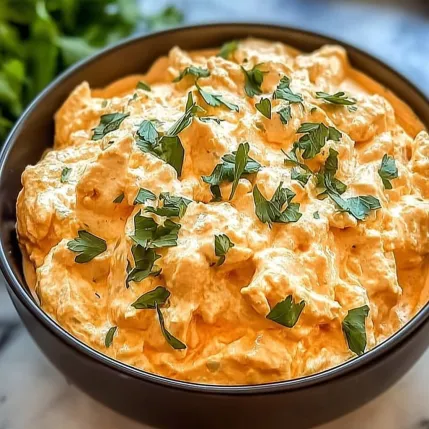 A bowl of food with green and orange toppings.