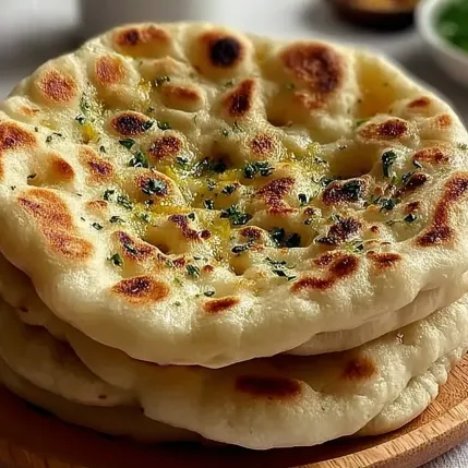 A stack of pita bread with herbs on top.