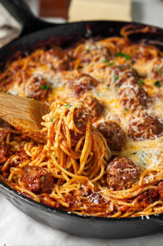 A bowl of spaghetti with meatballs and cheese.