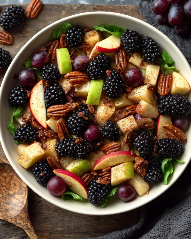 A bowl of fruit salad with apples, blackberries, and pecans.