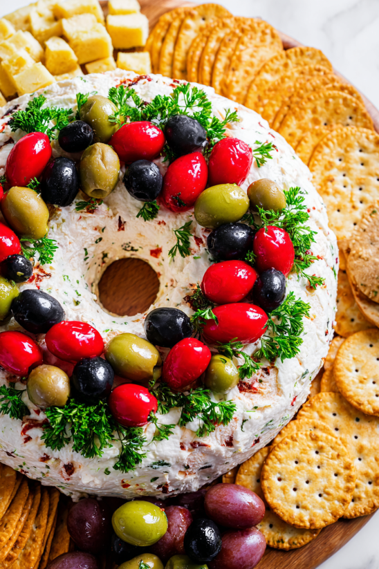 A cheese ball wreath with olives and crackers.