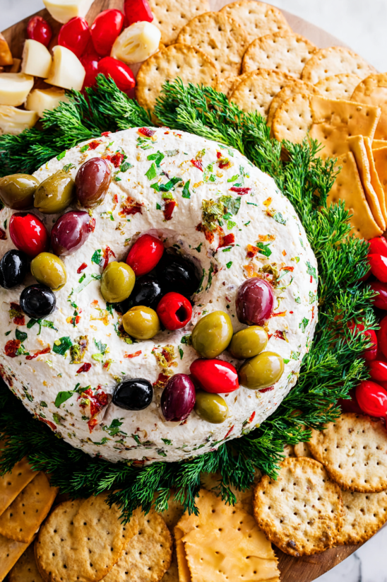 A cheese ball wreath with olives and crackers.
