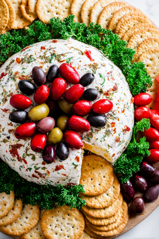 A cheese ball wreath with olives and crackers.