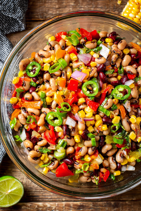 A bowl of cowboy caviar with beans, corn, peppers, and onions.