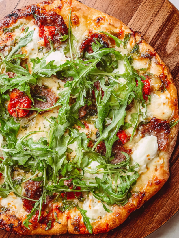 A close up of a pizza with greens and cheese.
