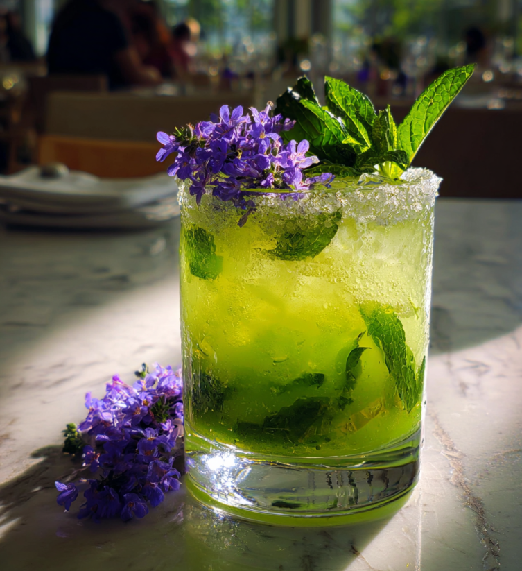 A glass of green drink with mint and lavender.