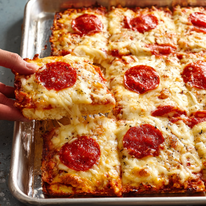 A hand picking up a slice of pizza.