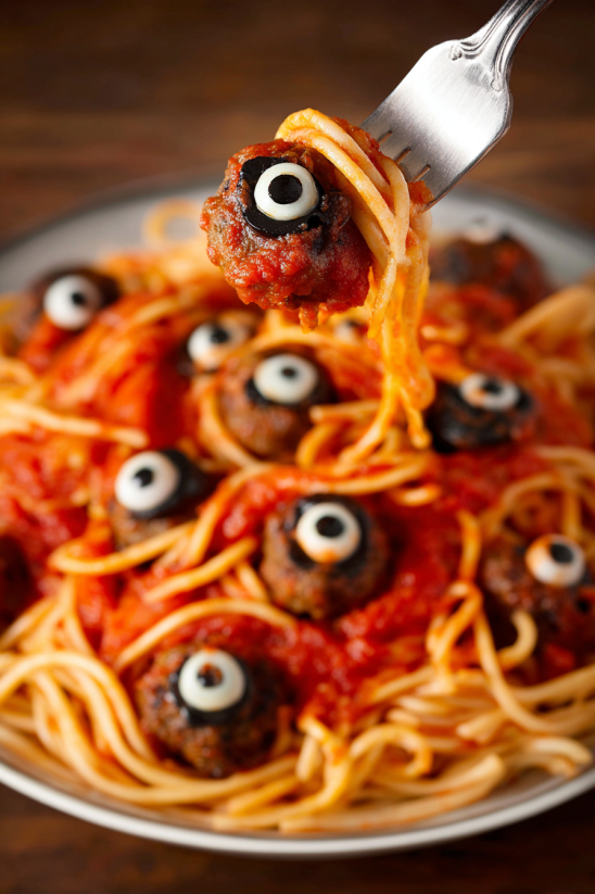 A plate of spaghetti with black olives and eyeball pasta.